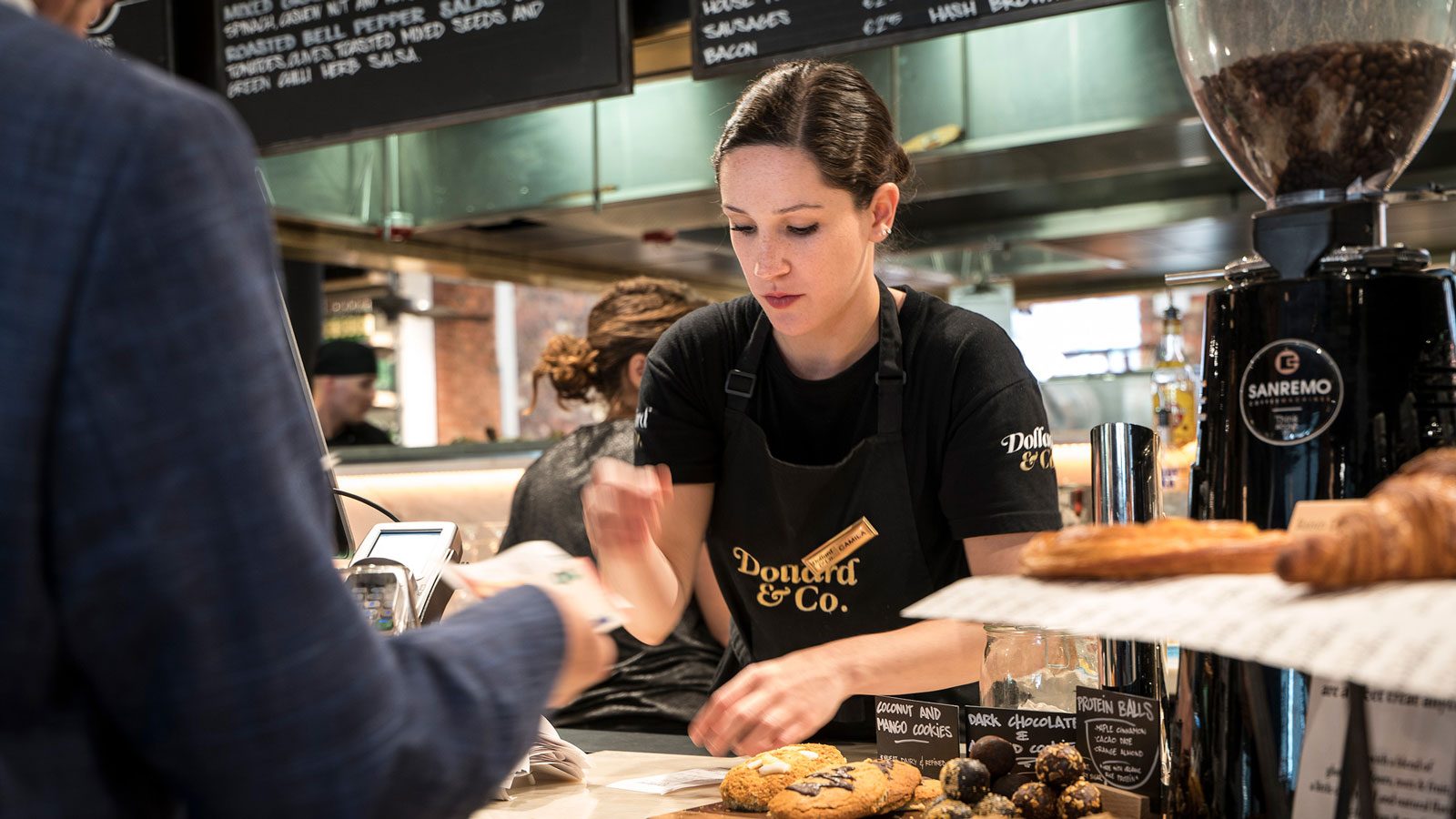 Woman working behind food counter in Ireland, helping customer in cafe